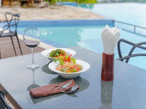 360 Resort في سيهانوكفيل: طاولة مع وعاء من السلطة وكأس من النبيذ