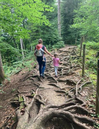 a woman and a child walking on a forest trail at Ferienwohnung Schönenbühl in Hittisau