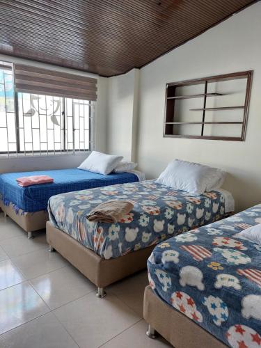 a bedroom with three beds and a tv on the wall at Casa Estación Modelia, near to the airport. in Bogotá