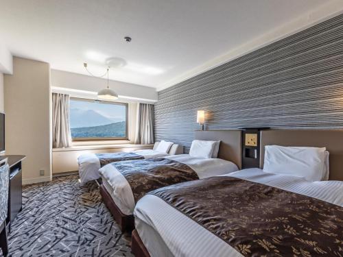 una camera d'albergo con tre letti e una finestra di APA Hotel & Resort Joetsu Myoko a Myoko