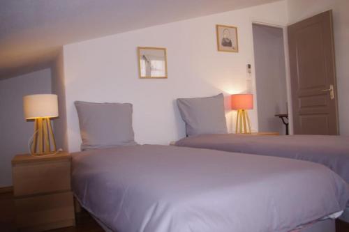 チュイルにあるGite la tuilerieのベッド2台 ホテルルーム ランプ2つ付