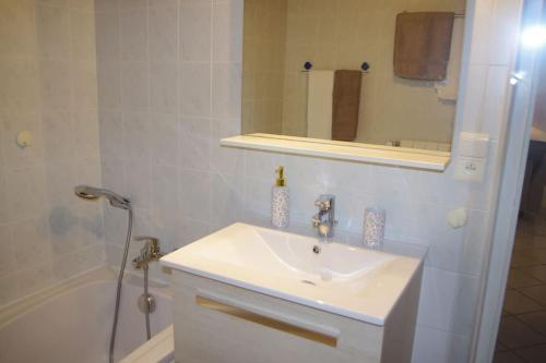 een badkamer met een wastafel, een spiegel en een bad bij Gite la tuilerie in Thuir