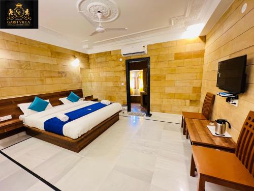 Schlafzimmer mit einem Bett und einem Flachbild-TV in der Unterkunft Hotel Garh Vila in Jaisalmer