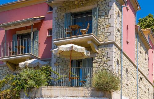 un bâtiment rose avec deux chiens sur un balcon dans l'établissement PargaMondo Countryliving, à Parga