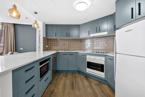a kitchen with blue cabinets and white appliances at Chatswood Hub Self- Catering 815 in Sydney