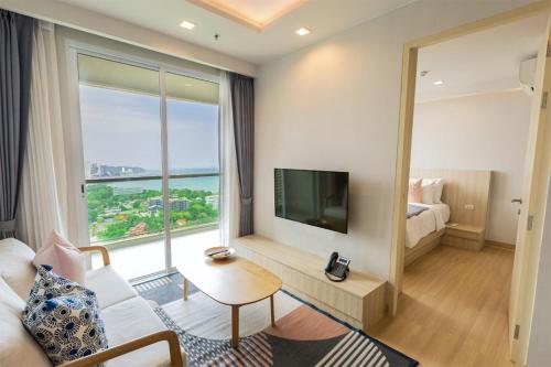 een woonkamer met een groot raam en een televisie bij Yuu Residence in Si Racha