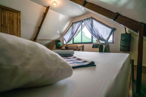 Schlafzimmer mit einem Bett mit einem Kissen und einem Fenster in der Unterkunft Bangka Hostels in El Nido