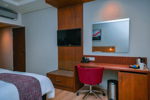 a bedroom with a desk and a bed and a red chair at Crowne Plaza - Dar Es Salaam by IHG in Dar es Salaam