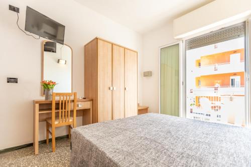 a bedroom with a bed and a desk and a television at Hotel Haway in Rimini