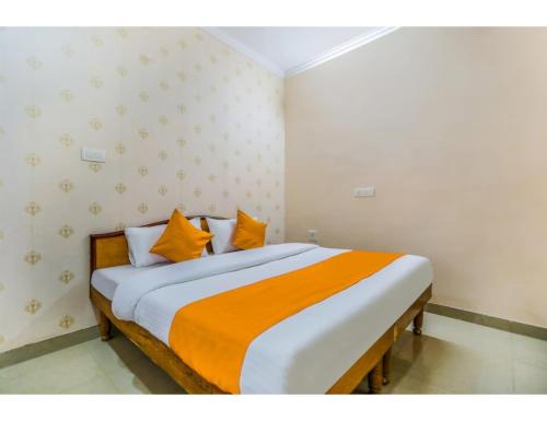 1 dormitorio con 1 cama con sábanas de color naranja y blanco en Hotel Rukmani Palace, Sri Ganganagar, en Gangānagar