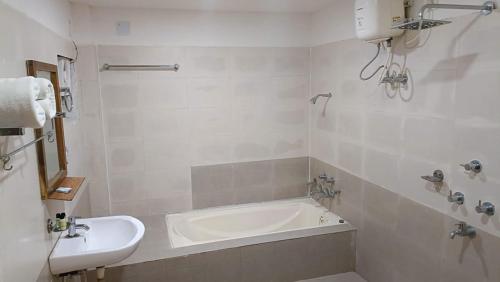 a white bathroom with a tub and a sink at Wild Dunes Konark in Bālighāi