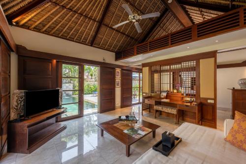 een woonkamer met een plafondventilator en een tafel bij Jimbaran Puri, A Belmond Hotel, Bali in Jimbaran