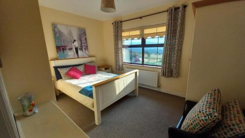 een slaapkamer met een bed met rode kussens en een raam bij Cuckoo Tree House Glengarriff Beara Peninsula in Glengarriff