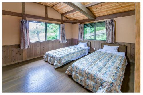 two beds in a room with two windows at 但馬長寿の郷　宿泊棟「夢」ロッジ in Yabu