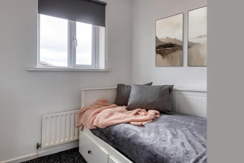 Cosy Three bedroom house in Radcliffe في رادكليف: سرير في غرفة بها نافذتين