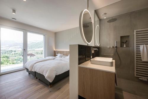 a bedroom with a bed and a sink and mirror at Astor Apartments in Valdaora