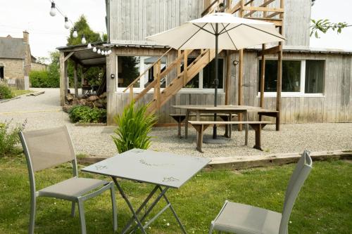 a patio with a table and chairs and an umbrella at LOFT Le chant des Oiseaux proche Mont St Michel in Pleine-Fougères