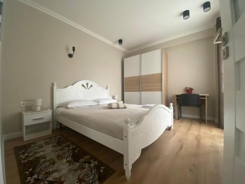 a white bedroom with a white bed and a mirror at Central Park Apartment in Cluj-Napoca