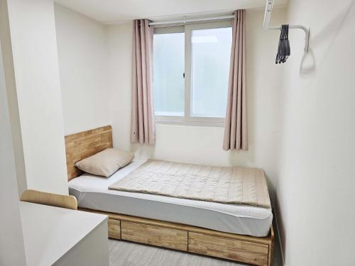 Cama pequeña en habitación con ventana en BoA Travel House en Seúl