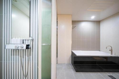 a bathroom with a shower and a tub and a sink at Hotel Core in Naju