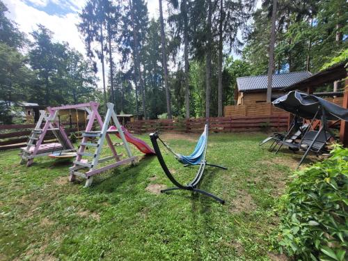 a yard with two swings and a playground at Domek Drewniany w Dolinie Symsarny in Lidzbark Warmiński