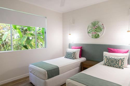 two beds in a room with a window at Beaches Holiday Apartments - Official Onsite Reception & Check In in Port Douglas