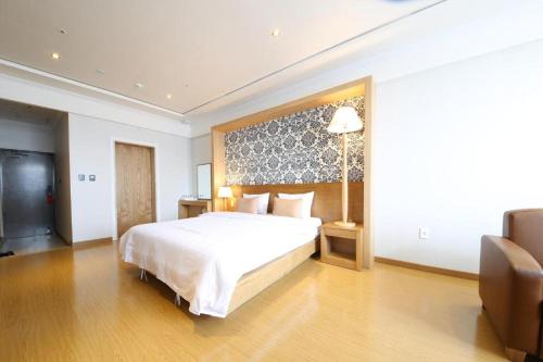 um quarto com uma grande cama branca e uma televisão em Lake 45 Hotel em Naju