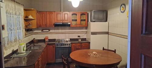 uma cozinha com armários de madeira, uma mesa e um frigorífico em Casa Linda em Salta