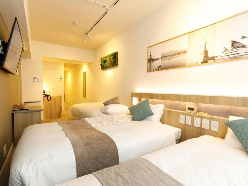 福岡市にあるプレジデントホテル博多のベッド3台とテレビが備わるホテルルームです。