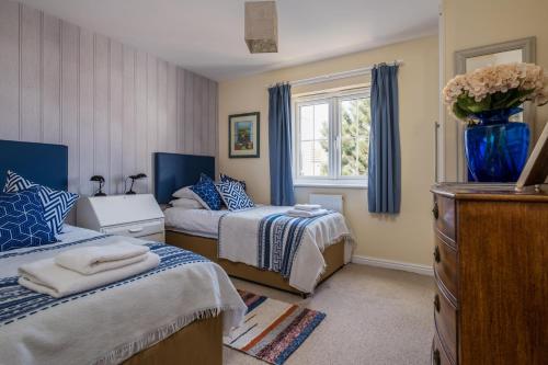 a bedroom with two beds and a vase of flowers at Camber Cottage in Camber