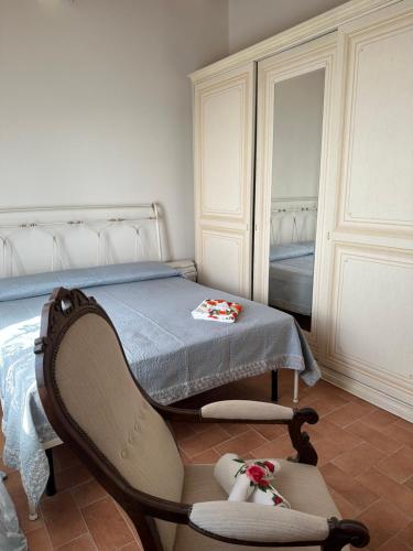 1 dormitorio con cama, silla y espejo en Villa i tre Cipressi, en Agnano