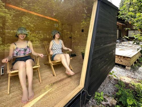 Dos mujeres sentadas en sillas en un patio en Denpaku Komatsu, en Komatsu