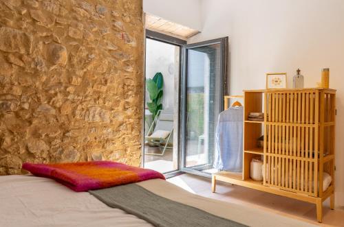 - une chambre avec un mur en pierre, un lit et une fenêtre dans l'établissement Empordanna, Apartamento con encanto en el corazón del Empordà, à Torroella de Montgrí