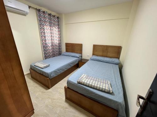 een kamer met 2 bedden en een raam erin bij صيفك في Grand Hills الكيلو ٦٠ الساحل الشمالي in Abû Zeira