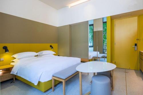 a bedroom with a large bed and a table at SongShan Lake PingShang Serviced Hotel in Huangcaolang