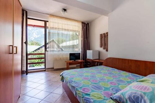 Schlafzimmer mit einem Bett, einem TV und einem Fenster in der Unterkunft Vila Emily in Buşteni