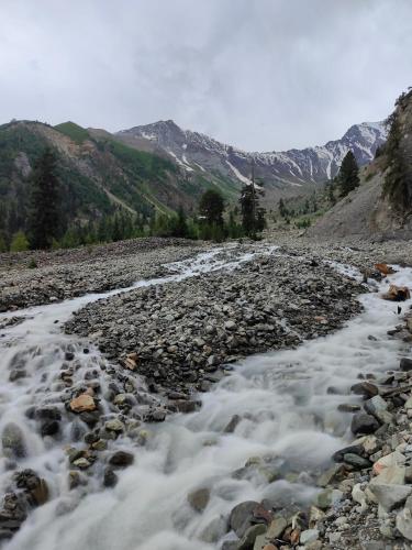 a stream on a rocky slope with mountains in the background at Rakaposhi Amin Hotel & Restaurant Pissan Hunza Nagar Gilgit Baltistan in Gilgit