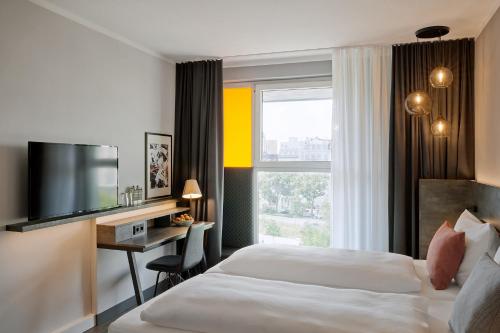 ein Hotelzimmer mit einem Bett, einem Schreibtisch und einem TV in der Unterkunft THE SCOTTY Hotel Hamburg in Hamburg