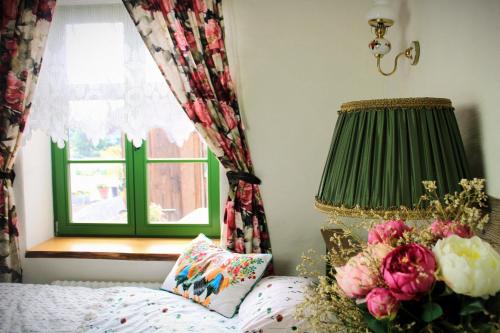 a bedroom with a bed with a lamp and a window at Osada Między Drzewami in Braniewo