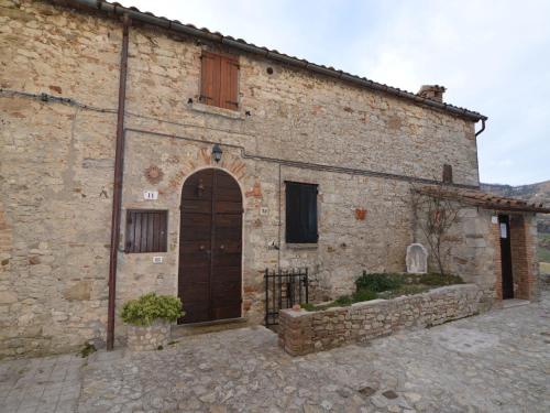 un antiguo edificio de piedra con una puerta marrón y un edificio en Appealing Apartment in Petrella Guidi with near Centre, en Petrella Guidi