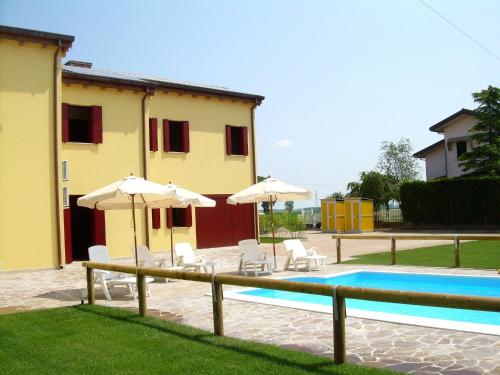 ein Pool mit Stühlen und Sonnenschirmen sowie ein Haus in der Unterkunft Cozy Holiday Home in Ariano nel Polesine with Swimming Pool in Il Piano
