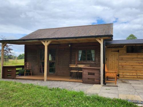 a large wooden cabin with a deck with a table at The Meadow in Lapworth