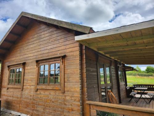 a log cabin with a deck and a picnic table at The Meadow in Lapworth