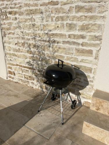 a charcoal grill sitting in front of a brick wall at Logement A / Clos des Saunières in Bligny-lès-Beaune