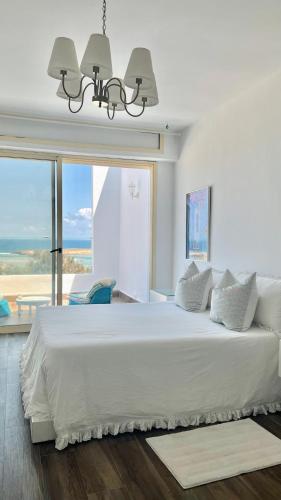 a bedroom with a large white bed with a large window at Maison Simonetta in Oualidia