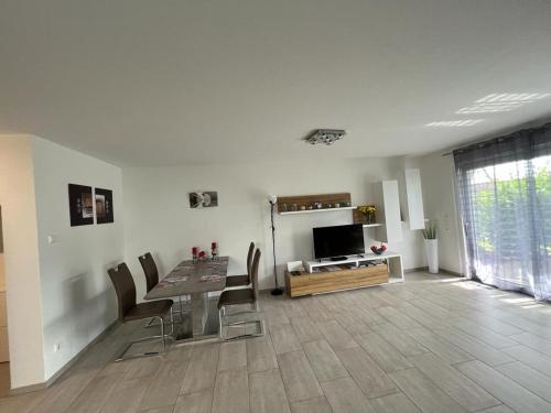 ein Wohnzimmer mit einem Tisch, Stühlen und einem TV in der Unterkunft Ferienwohnung am Strandbad in Friedrichshafen