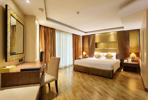 a hotel room with a bed and a desk at Nova Gold Hotel Pattaya in Pattaya