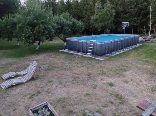 uma piscina com um banco e um cesto de basquetebol em PENSJONAT W LESIE em Tuczno