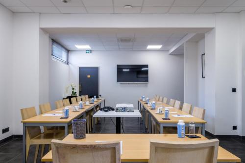 a conference room with wooden tables and chairs and a screen at Best Western Hôtel Journel Antibes Juan-les-Pins in Antibes
