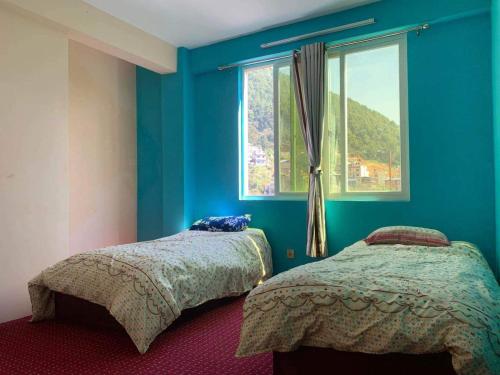 two beds in a room with blue walls and a window at Season homestay in Kathmandu